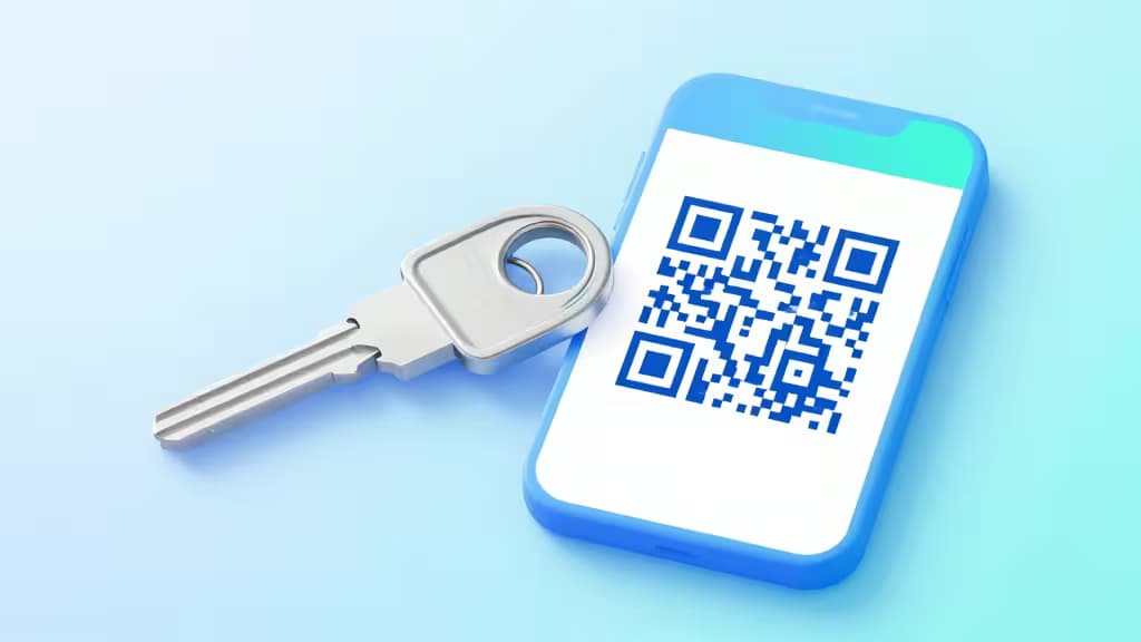 A metallic key rests beside a smartphone displaying a QR code, symbolizing secure 2FA backup methods.