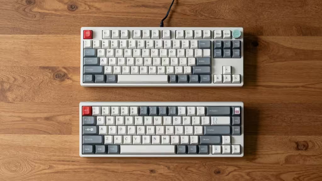 Two compact mechanical keyboards with low-profile keys rest on a wooden surface, showcasing ergonomic design for small hands.