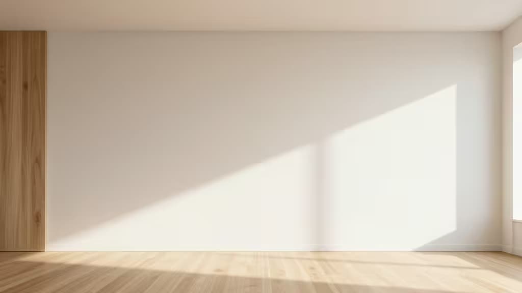 Sunlight streams across light wood floors and white walls, casting geometric shadows in a minimalist, empty room.