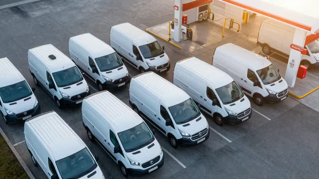 Flotte von weißen Transportern an einer Tankstelle bei Sonnenaufgang