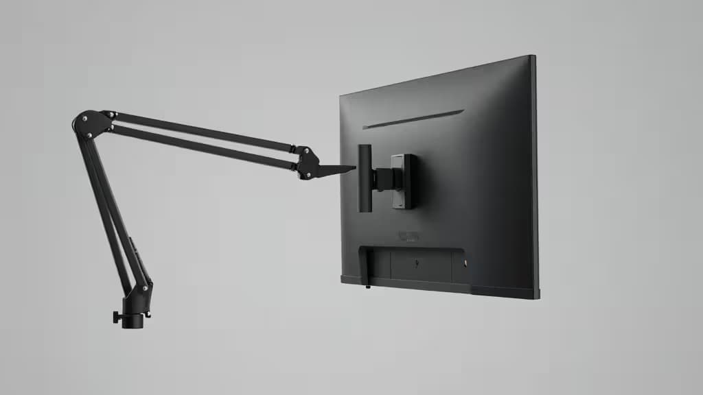 A large monitor mounted on a gas-spring desk arm extending from a desk clamp, shown at a three-quarter angle with minimalist studio lighting.