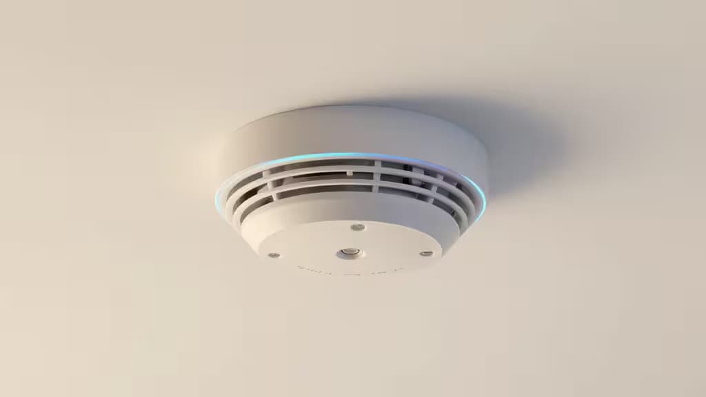Um detetor de fumo branco com anel azul luminoso montado no teto, indicando conectividade ativa com casa inteligente.