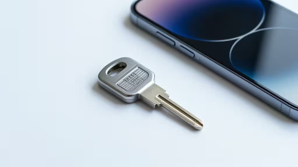 Физический ключ безопасности FIDO2 рядом с современным смартфоном на минималистичной белой поверхности