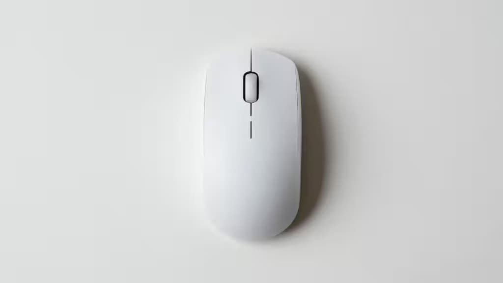 A compact vertical wireless mouse resting on a clean light desk surface, photographed from above in soft natural light.