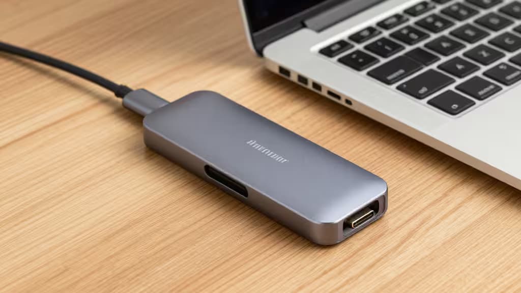 Sleek aluminum USB-C hub connects to MacBook Air on wood desk.