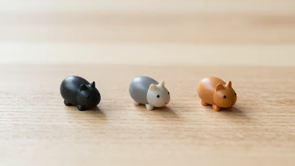 Quatre souris ergonomiques de couleur noire, grise et marron disposées sur un bureau en bois clair, lumière naturelle douce