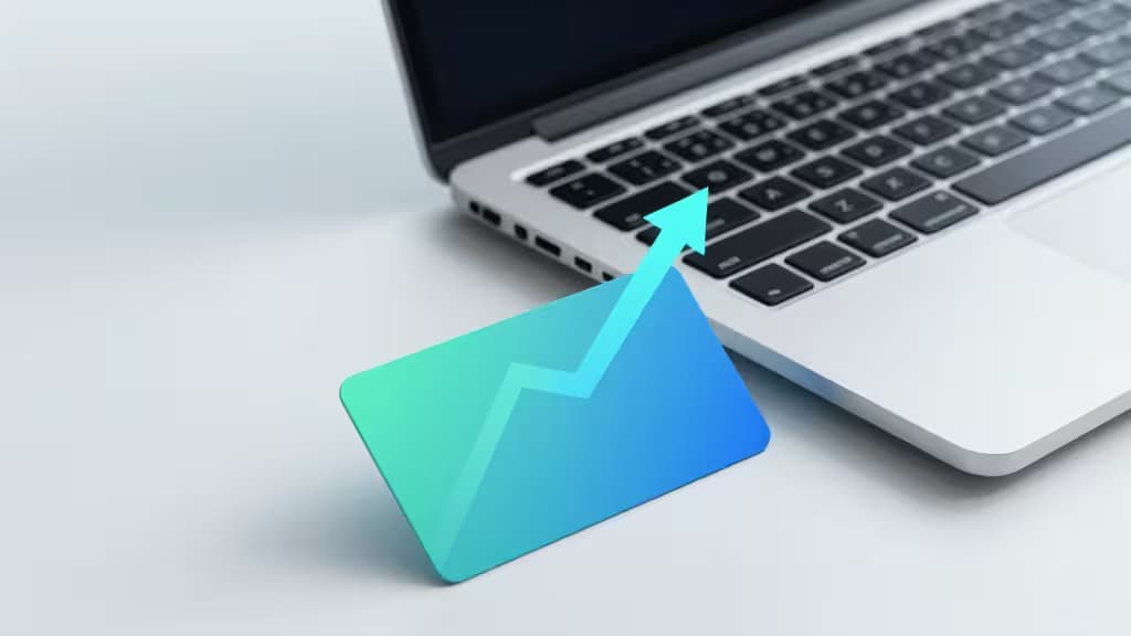 A glowing teal growth arrow rises from a sleek fintech card beside a silver laptop on a white desk.