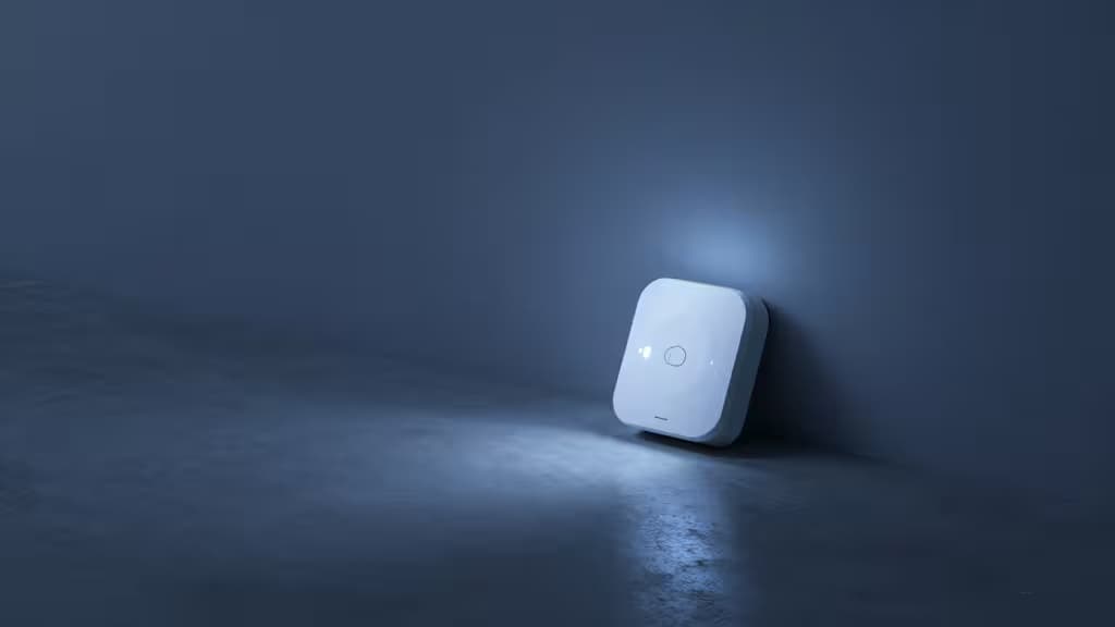 Sótano moderno con iluminación azul tenue y un sensor de fugas inteligente sobre el suelo de hormigón junto a una tubería de agua