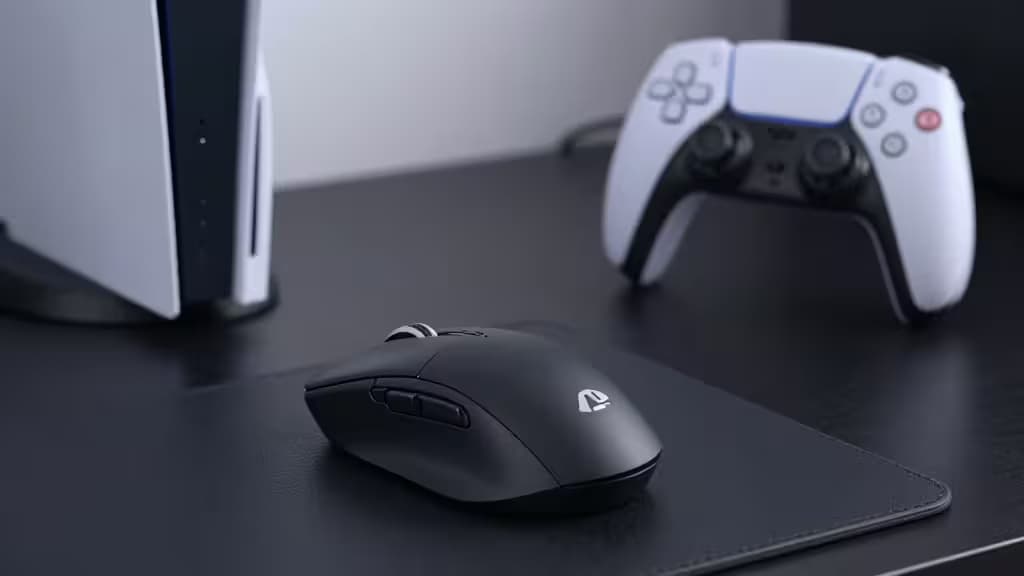 A black gaming mouse rests on a mousepad beside a white PS5 controller.