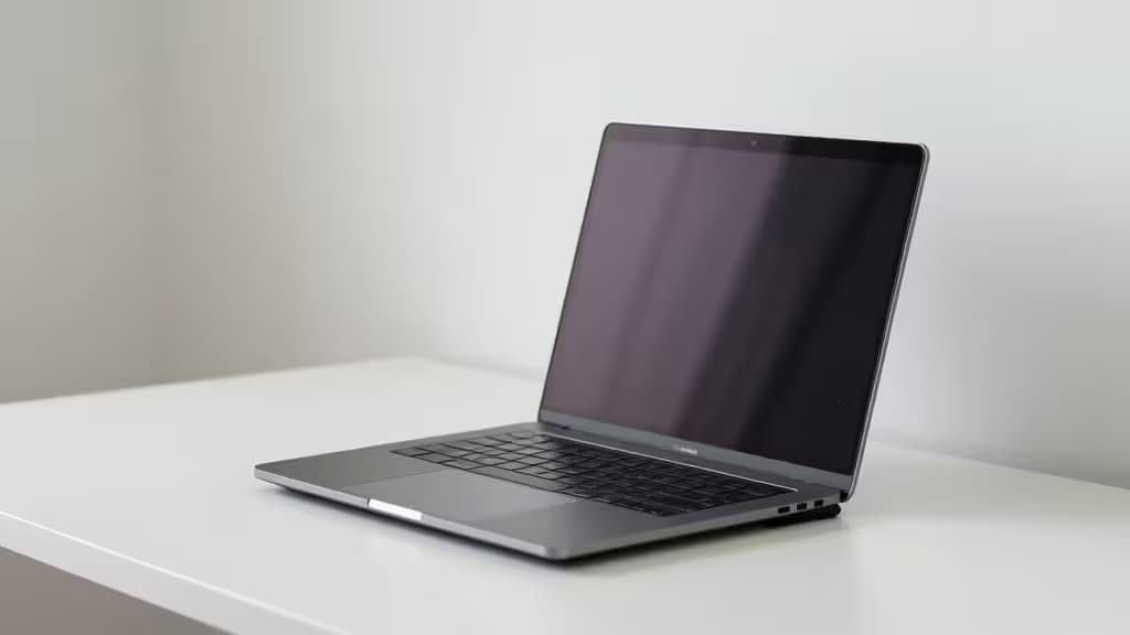 A sleek silver laptop rests on a minimalist white desk, angled for ergonomic viewing.