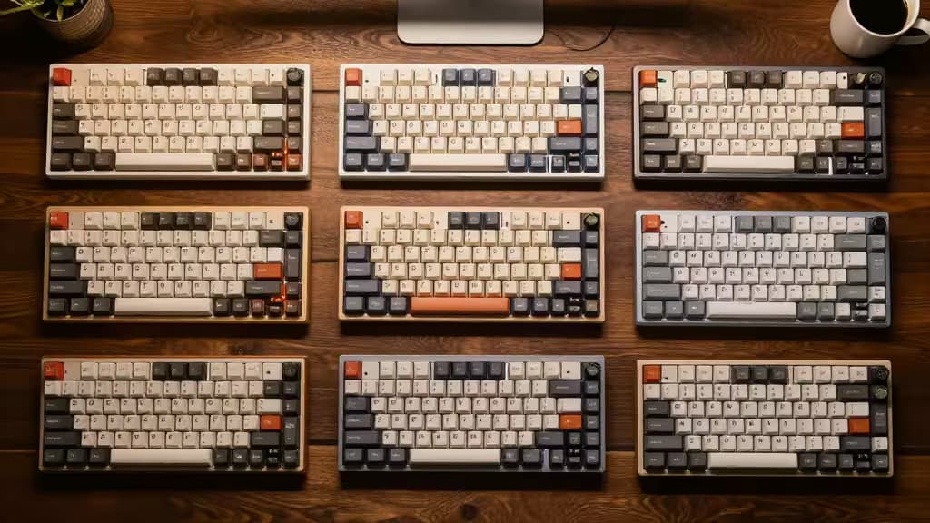 Nine mechanical keyboards with varied keycaps arranged in a 3x3 grid on a wooden desk.