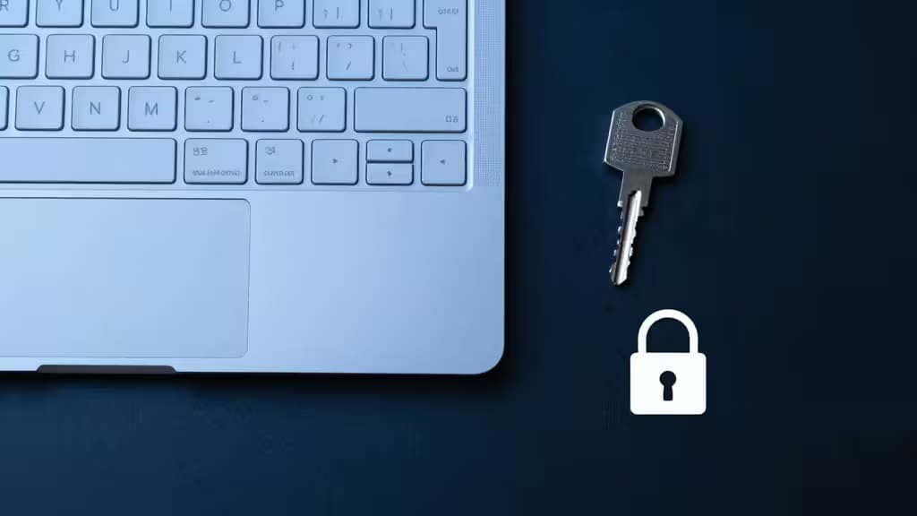 Una tastiera per laptop, una chiave metallica e un'icona a forma di lucchetto su una superficie scura simboleggiano la gestione sicura delle chiavi API.
