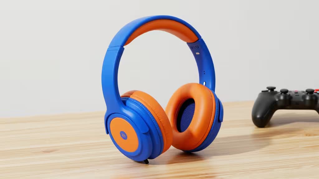 Headset gaming azul e laranja para crianças sobre uma secretária de madeira ao lado de um comando preto.