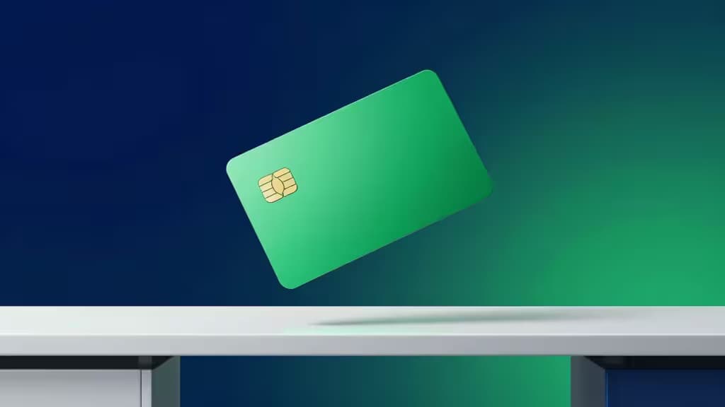 A green corporate card floats above a white desk against a blue-green gradient background, symbolizing fintech innovation for startups.