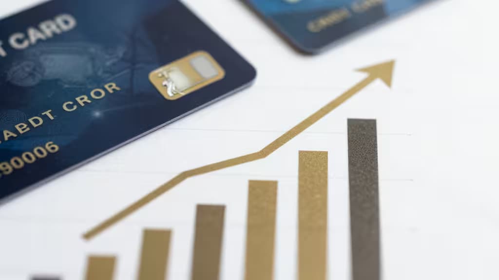 Dark blue credit cards rest beside a rising gold bar chart on white paper.