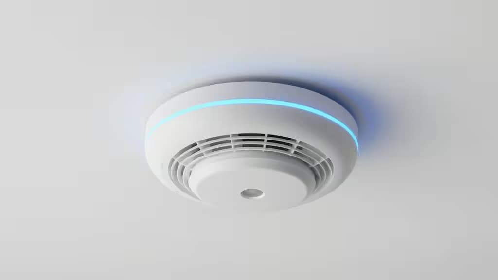 Détecteur de fumée intelligent blanc monté au plafond dans un intérieur moderne, avec halo lumineux bleu évoquant la maison connectée