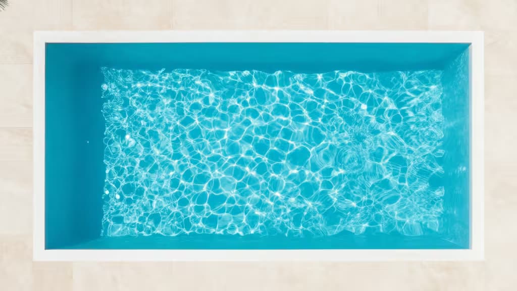 Rectangular white pool with turquoise water and rippling light patterns on beige tiled background.